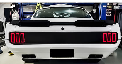White car with black rear wing and red LED lights in a garage setting
